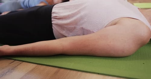 Adults Lying on Exercise Mats Relaxing in Studio