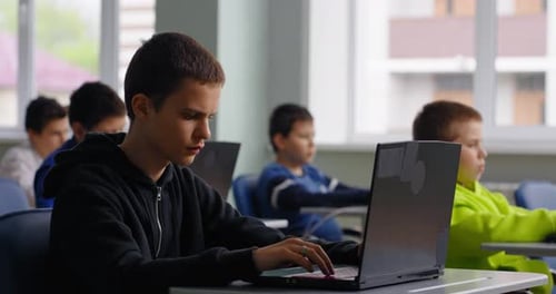Jugendliche Schüler im computergestützten Klassenzimmer von Gymnasiasten, die mit Laptops arbeiten