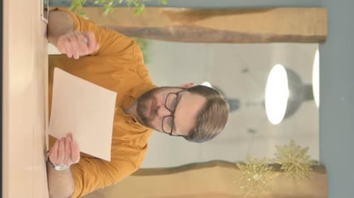 Man Reviewing Document at Desk Indoors