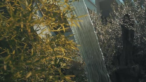 Small waterfall in a fake artificial pond with leafs around it.