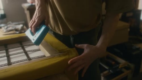 Adult Reupholsters Furniture Frame with Staple Gun