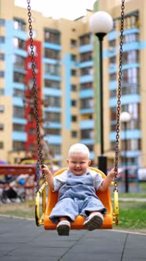Lovely Caucasian baby boy swaying on the swing.