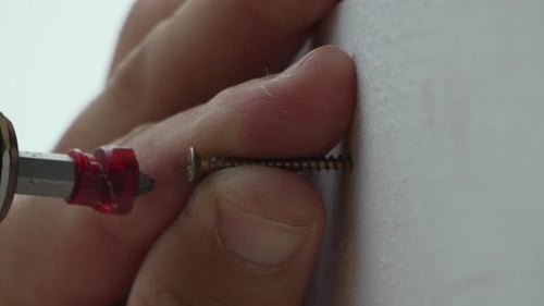 A Man Hands Using a Power Tool Fastens a Board with a Screw Slow Motion