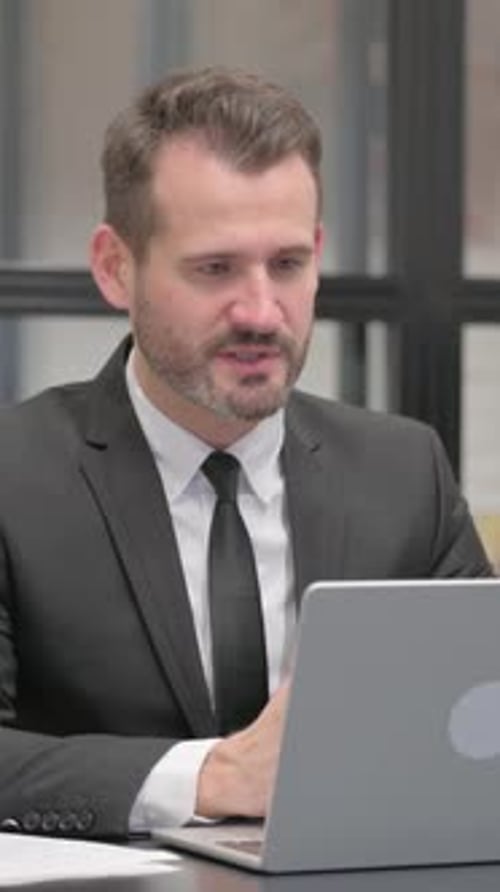 Man in Suit Talking on Laptop Video Call