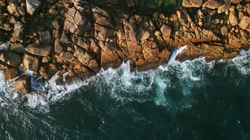 Vagues aériennes d'un bleu vif s'écrasant contre la côte tropicale, vue à vol d'oiseau, mouvement dynamique de l'eau