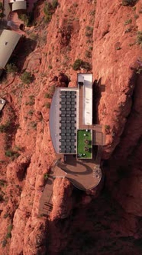 Vertical Top Down Aerial View, Futuristic House With Solar Panels Atop of Cliff in Desert Landscape