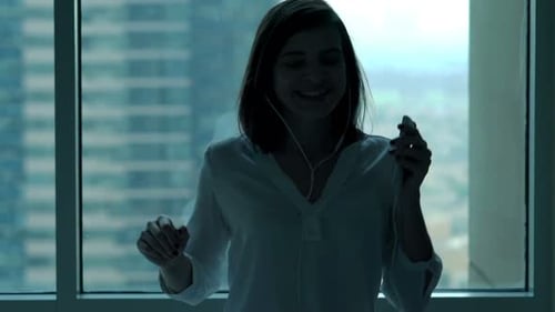 Businesswoman Listening to Music and Dancing by Window in Office, Super Slow