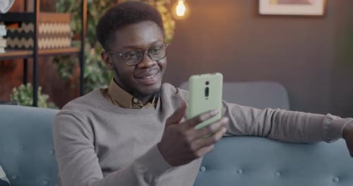 Young Adult Man Video Chatting on Smartphone Indoors