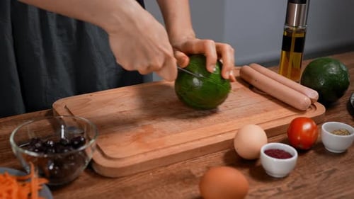 Woman Cutting Avocado on Cutting Board in Kitchen