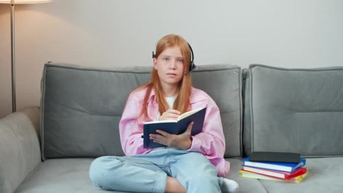 Girl Studying With Headset and Taking Notes