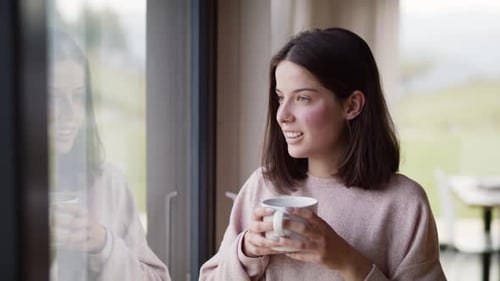 Young Woman Enjoying Hot Drink by Window