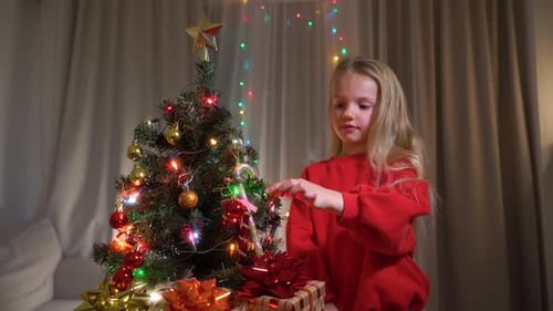 A little girl decorates a Christmas tree