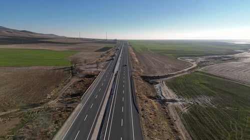 Aerial Car Drives Along a Modern Highway Surrounded By Open Green Fields