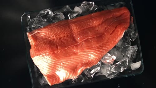 Filete de salmón cayendo sobre el hielo filmado en cámara lenta a 1000 fps