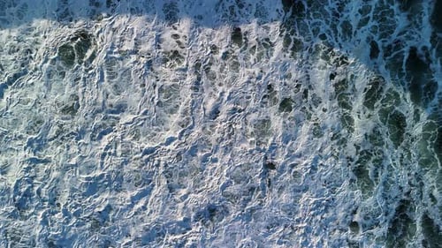 Raw energy of large waves crashing in the sea creating unique pattens amongst the foaming ocean