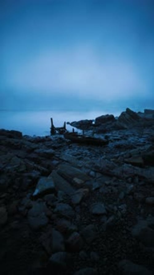 Tranquil Twilight at the Rocky Shore with Calm Waters and Fog