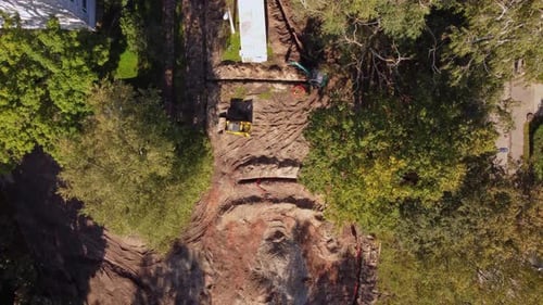 Construction site with excavation work near residential homes and trees