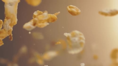 Hochwertige Zeitlupenaufnahme von Cornflakes, die vor einem warmen und sonnigen Hintergrund fliegen und sich drehen