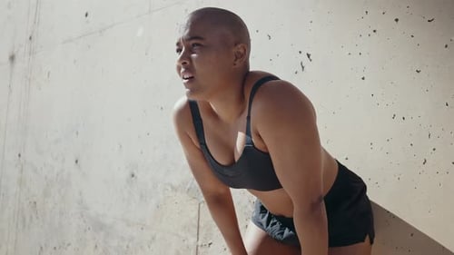 Tired Woman Resting Against Concrete Wall After Workout