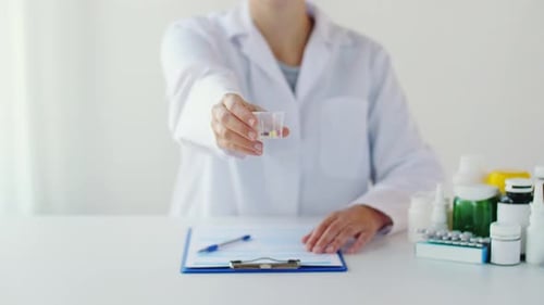 Doctor showing pills cup and prescribing medication at hospital
