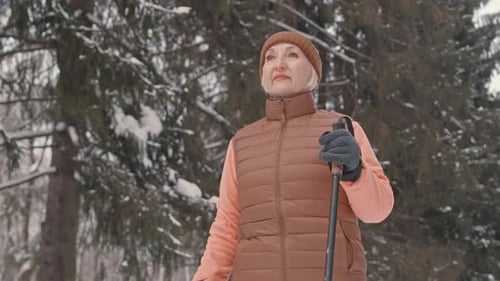 Elderly Woman Nordic Walking in Winter Forest