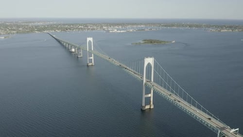 Drohnenaufnahme einer großen Brücke, die das Wasser überquert, sich vorwärts bewegt und langsam nach unten kippt.
