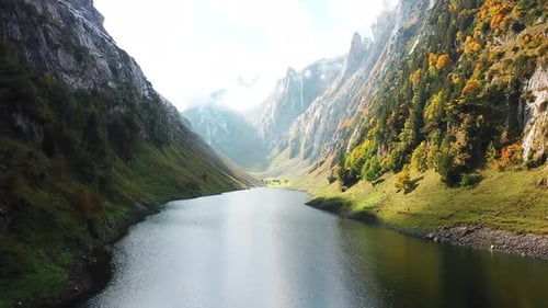 Drone traveling through Fahlensee lake reflecting majestic mountains in autumn, Switzerland