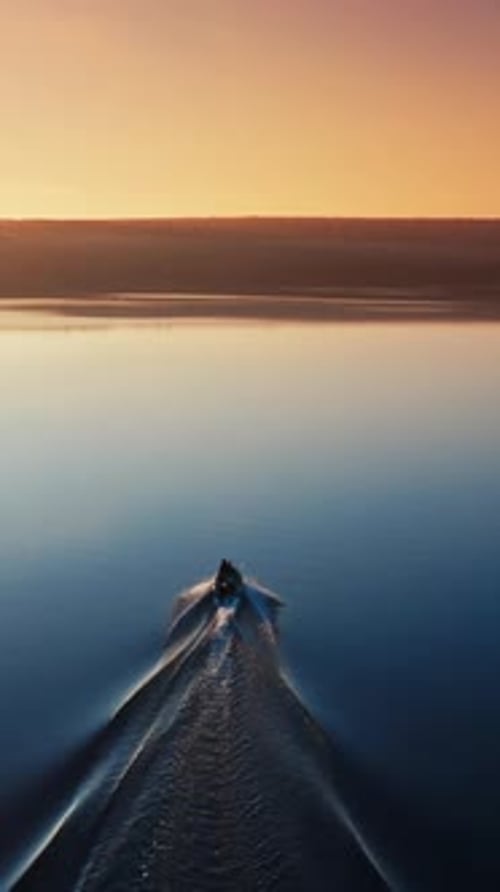 Aerial view of a motor boat at sunset. Calm water in a blue lake in the evening.