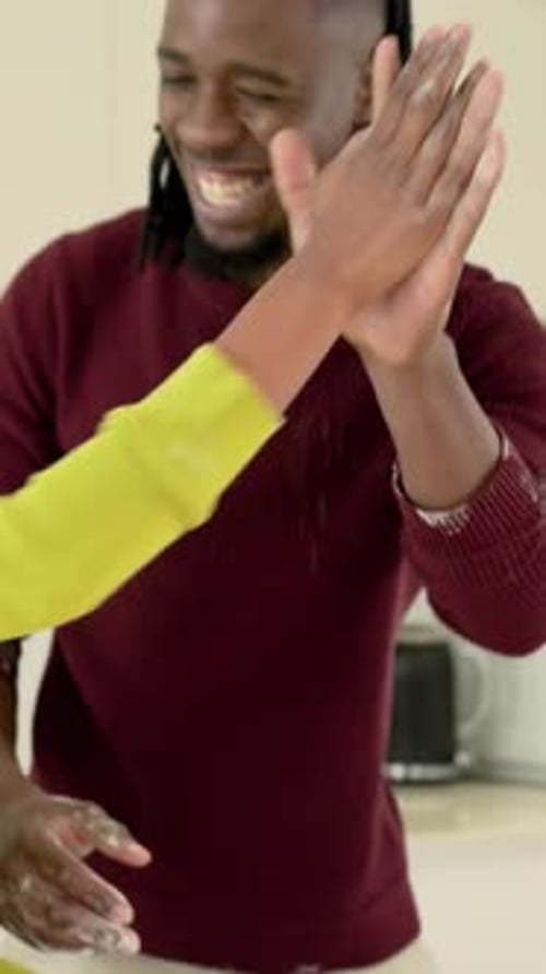 Vidéo verticale : Un homme et une femme tapent des mains farineuses, étalent une garniture aux cerises sur le comptoir pour une tarte