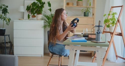 Woman Wearing Headphones Writing at Desk Indoors