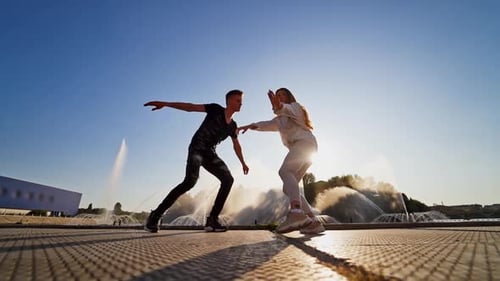 Dancers against beautiful fountain. Young couple performing a modern dance on the urban background.