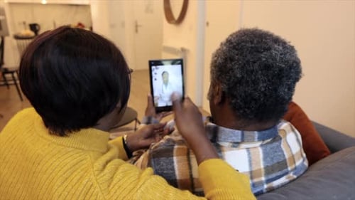 African American senior couple talk to their doctor over video call from home