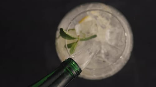 Pouring Clear Liquid Into Glass With Ice and Lemon