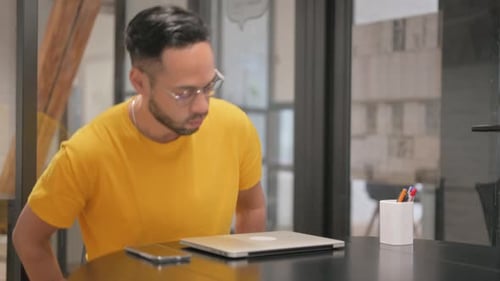 Young Adult Opens Laptop at Modern Office Desk