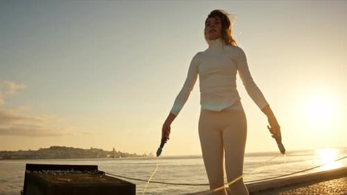 Young Sporty Woman Jumping Rope at Sunrise By the Sea
