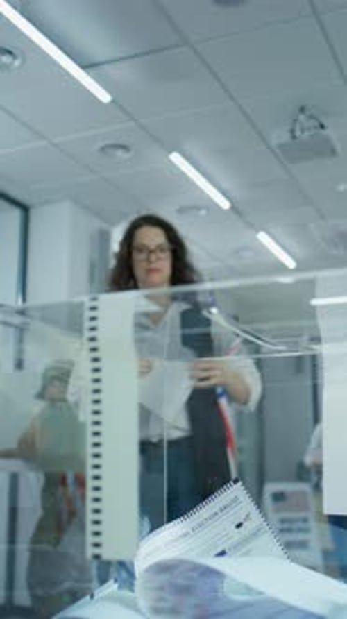 Caucasian Woman Puts Voting Bulletin in Box at Polling Station