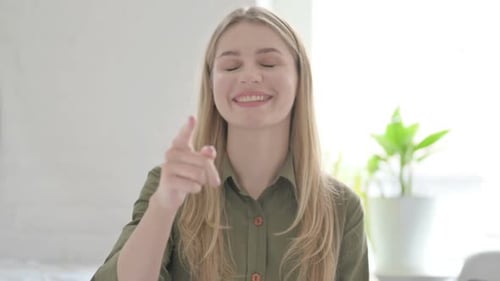 Smiling Woman Points at the Camera Indoors