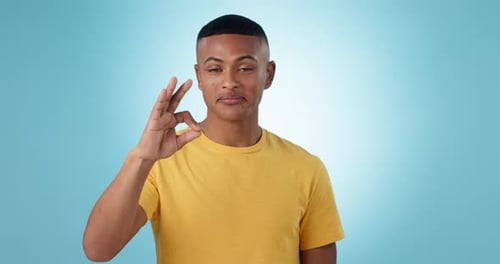 Young Adult Makes Ok Gesture on Blue Background
