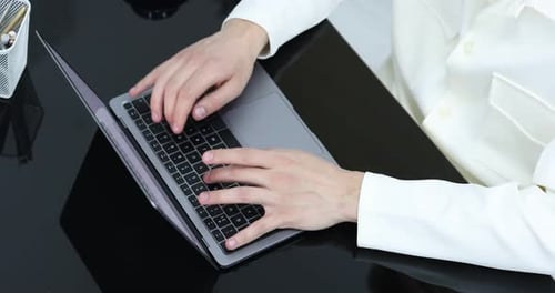 Man working on laptop at desk in office, above view