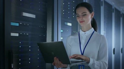 Confident and Beautiful Female IT Engineer is Working on Laptop in Data Center while Standing Befor