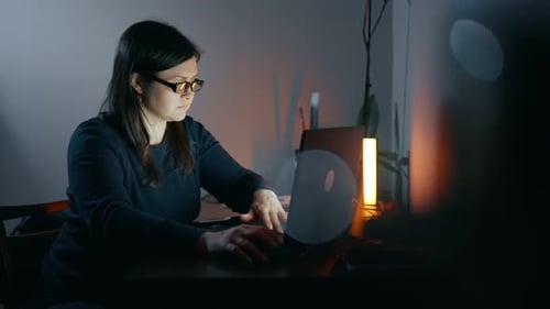 Inspired Lady Sits Focused on Work at Laptop in the Evening Alone