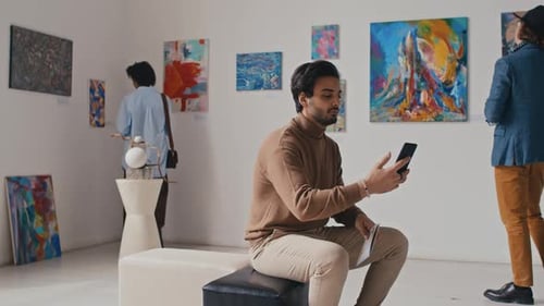 Young Male Visitor Taking Selfie at Exhibition in Art Gallery