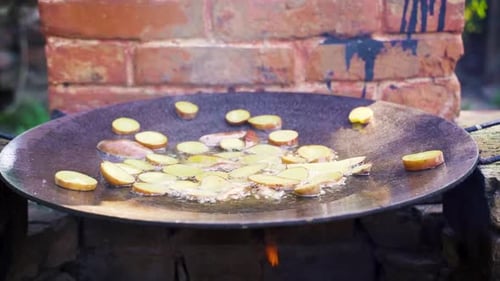 New potatoes are frying over the open fire in the garden, slow motion.