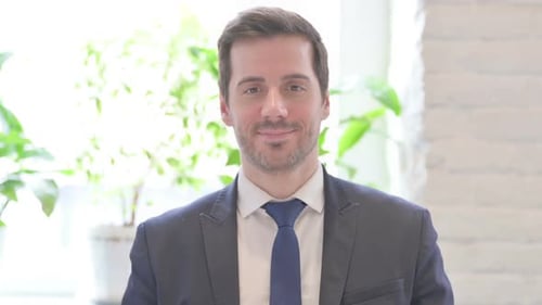 Portrait of Young Businessman Smiling at Camera in Office