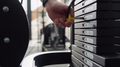 Trainer Inserts Pin Into Cable Machine Weight Stack For Resistance Adjustment