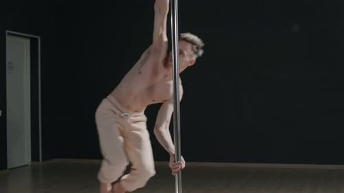Shirtless Man Pole Dancing on Black Background