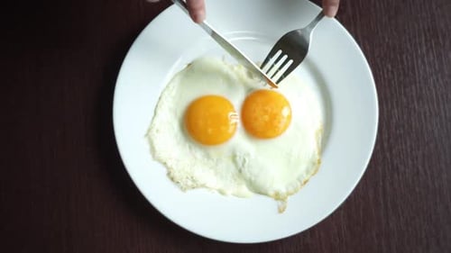 Fried Eggs Eating. Top View Of Fried Eggs Eating With Fork And Knife. Traditional Breakfast Eggs ...