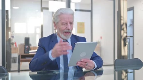 Senior Businessman Celebrates While Using Tablet in Office