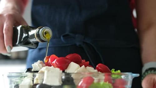Adding Olive Oil to Greek Salad in Glass Bowl