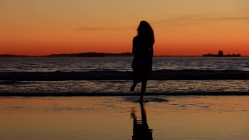 Asiatin genießt einen Strandspaziergang bei Sonnenuntergang. Zeitlupe.